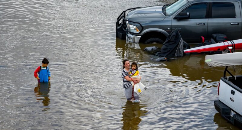 People wade through an rv park flooded by the