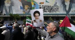 Iranian worshippers walk past a mural showing the late revolutionary founder Ayatollah Khomeini, right, Supreme Leader Ayatollah Ali Khamenei, left, and Basij paramilitary force, as they hold a poster of Ayatollah Khomeini and Iranian and Palestinian flags in an anti-Israeli gathering after their Friday prayer in Tehran, Iran, Friday, April 19, 2024.