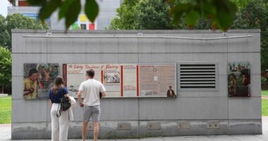 FILE - People look an informational panel at President