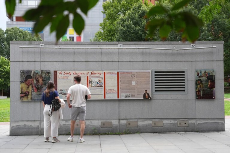 FILE - People look an informational panel at President