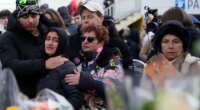 People mourn behind flowers near the sealed off Le Constellation bar, where a devastating fire left dead and injured during the New Year