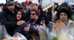 People mourn behind flowers near the sealed off Le Constellation bar, where a devastating fire left dead and injured during the New Year