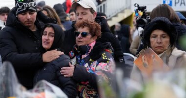 People mourn behind flowers near the sealed off Le Constellation bar, where a devastating fire left dead and injured during the New Year