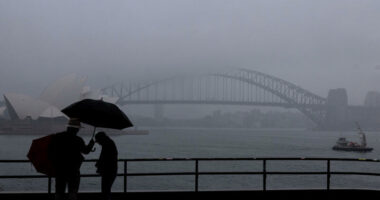 People are seen braving the rain and fog at Mrs Macquaries Chair this morning, Friday, 22 August 2025. After weeks of persistent rain, parts of the NSW coast have now recorded their wettest August in 126 years. Photo: Sam Mooy / The Sydney Morning Herald