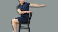 Handsome man exercising with chair at home