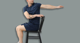 Handsome man exercising with chair at home