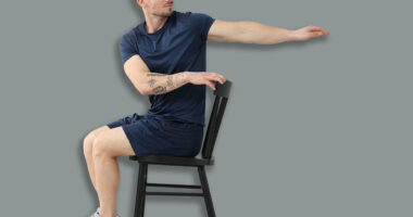 Handsome man exercising with chair at home