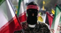 A member of the Iranian paramilitary Basij force holds an Iranian flag as he covers her face in the Palestinian and Lebanese militants style in an annual rally to mark Quds Day, or Jerusalem Day, to support the Palestinians in Tehran, Iran, Friday, April 5, 2024.