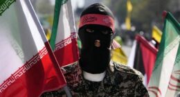 A member of the Iranian paramilitary Basij force holds an Iranian flag as he covers her face in the Palestinian and Lebanese militants style in an annual rally to mark Quds Day, or Jerusalem Day, to support the Palestinians in Tehran, Iran, Friday, April 5, 2024.