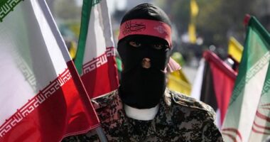 A member of the Iranian paramilitary Basij force holds an Iranian flag as he covers her face in the Palestinian and Lebanese militants style in an annual rally to mark Quds Day, or Jerusalem Day, to support the Palestinians in Tehran, Iran, Friday, April 5, 2024.