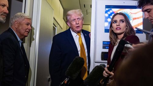 President Donald Trump speaks with reporters while in flight on Air Force One.