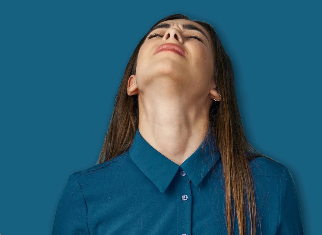 A woman with her hands up tilted her head back against a blue background