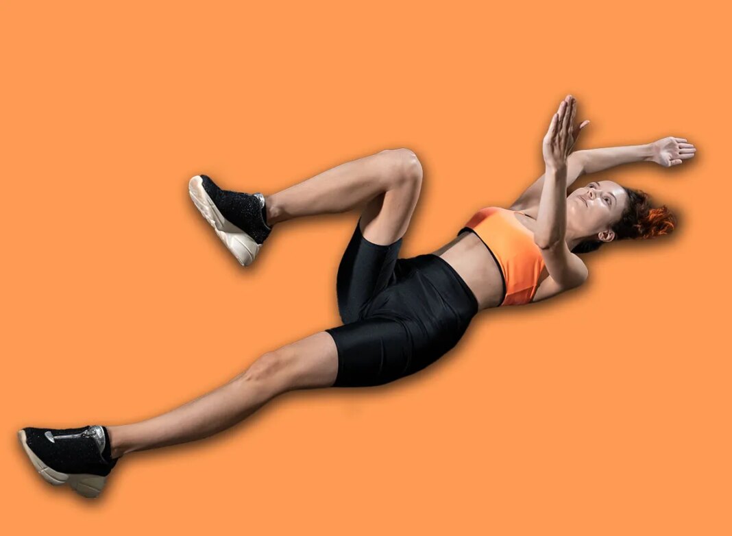 young woman exercising dead bug with personal trainer in gym
