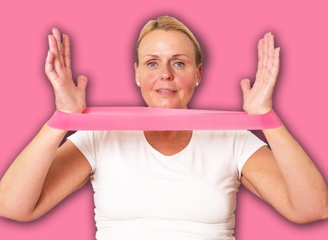 Active mature woman training arms with elastic band at home, promoting healthy lifestyle, rehabilitation, and senior fitness.