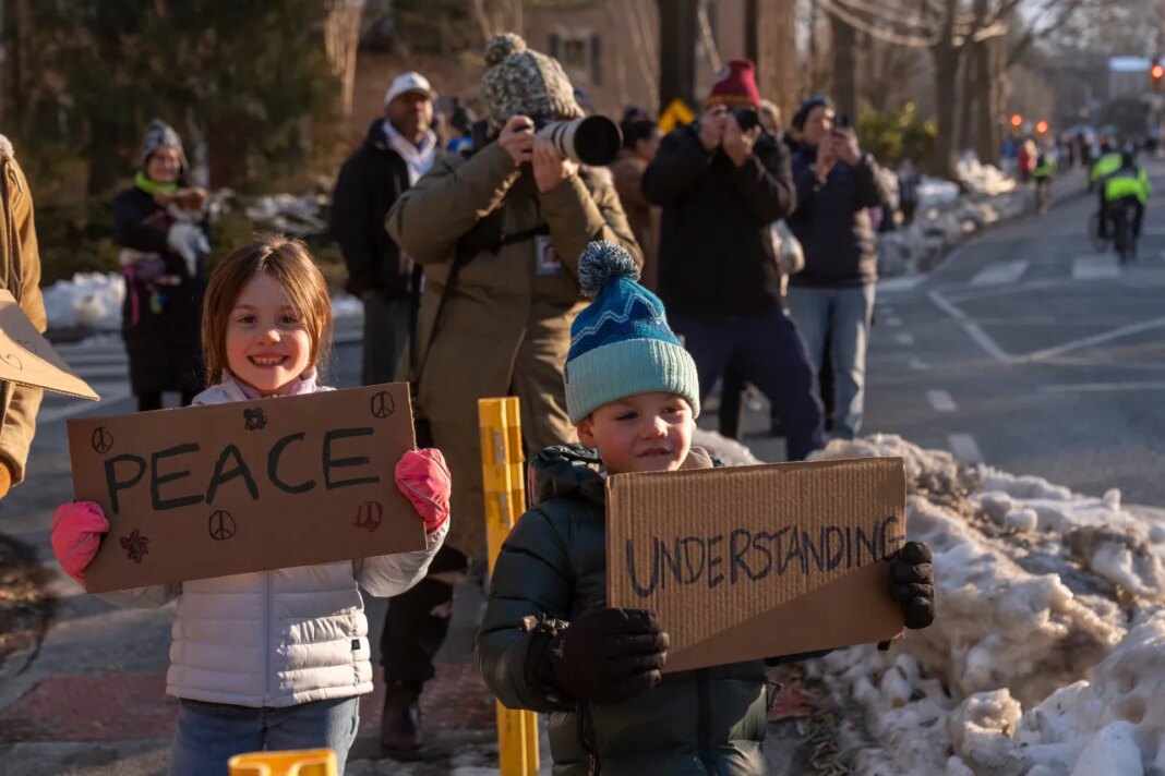Spectators watch as Buddhist monks who are participating in a Walk For Peace walk through a neighborhood on Tuesday, Feb. 10, 2026, in Washington. (AP Photo/Mark Schiefelbein)