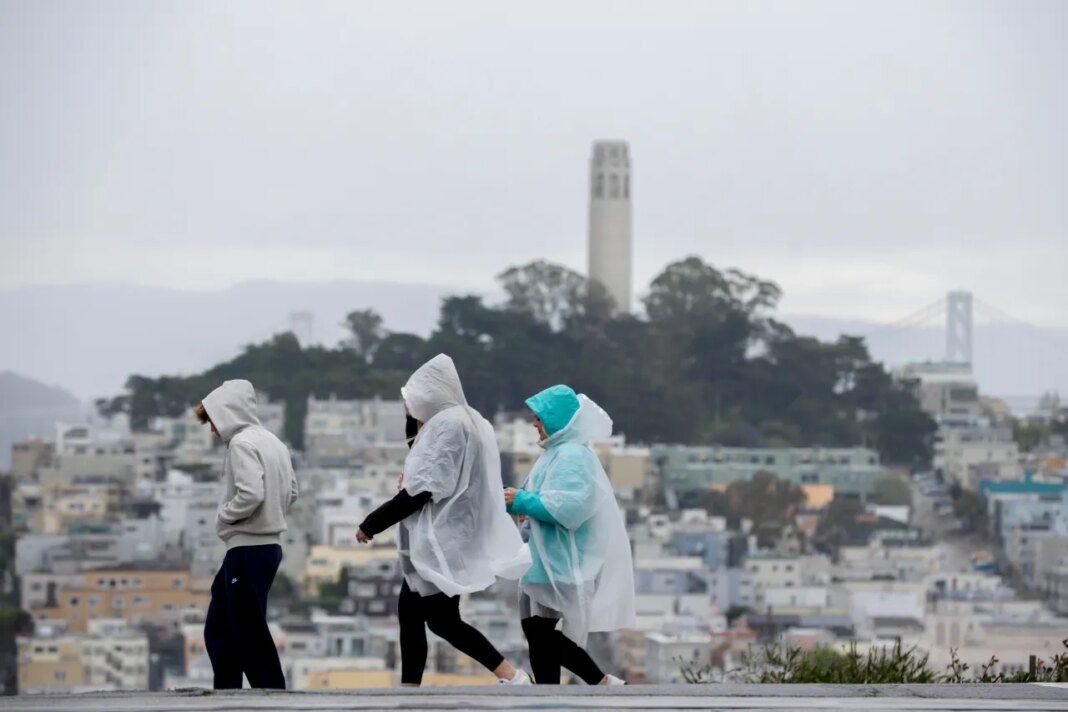 Visitors take in city views at Hyde and Lombard streets as rain begins to soak the Bay Area, in San Francisco, Sunday, Feb. 15, 2026. (Brontë Wittpenn/San Francisco Chronicle via AP)