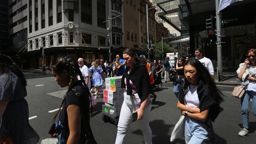 Pedestrians move across Market Street in Sydney, Australia. 