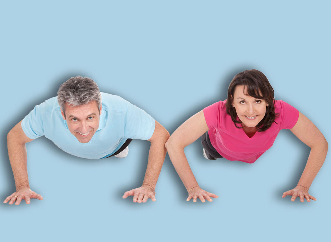 Active mature couple doing pushups. Isolated on white