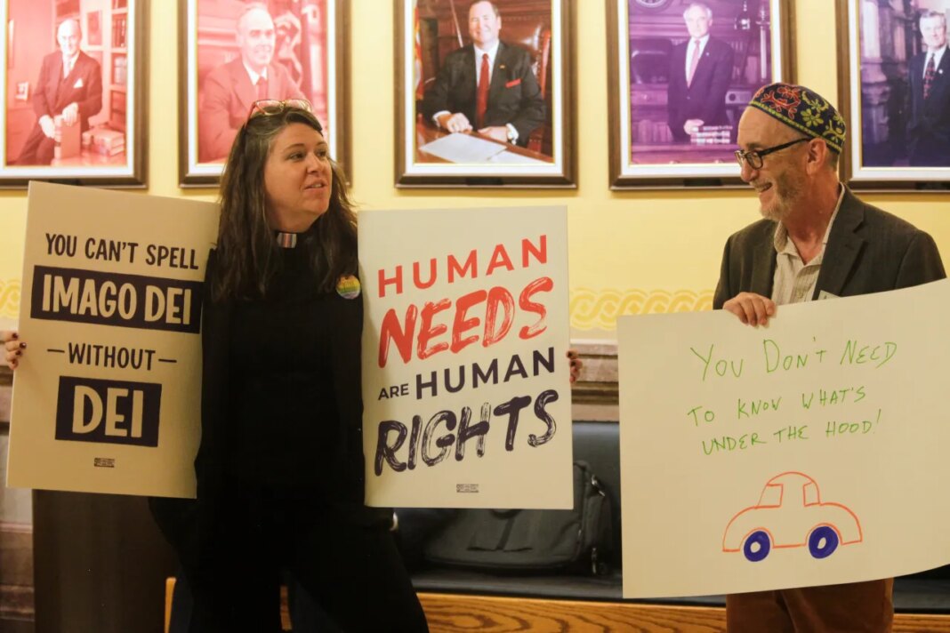 The Rev. Dr. Mandy Todd, left, pastor of Messiah Lutheran Church in Lindsborg, Kan., and Rabbi Moti Rieber, right, executive director of Kansas Interfaith Action, protest a new Kansas law that will invalidate hundreds of driver