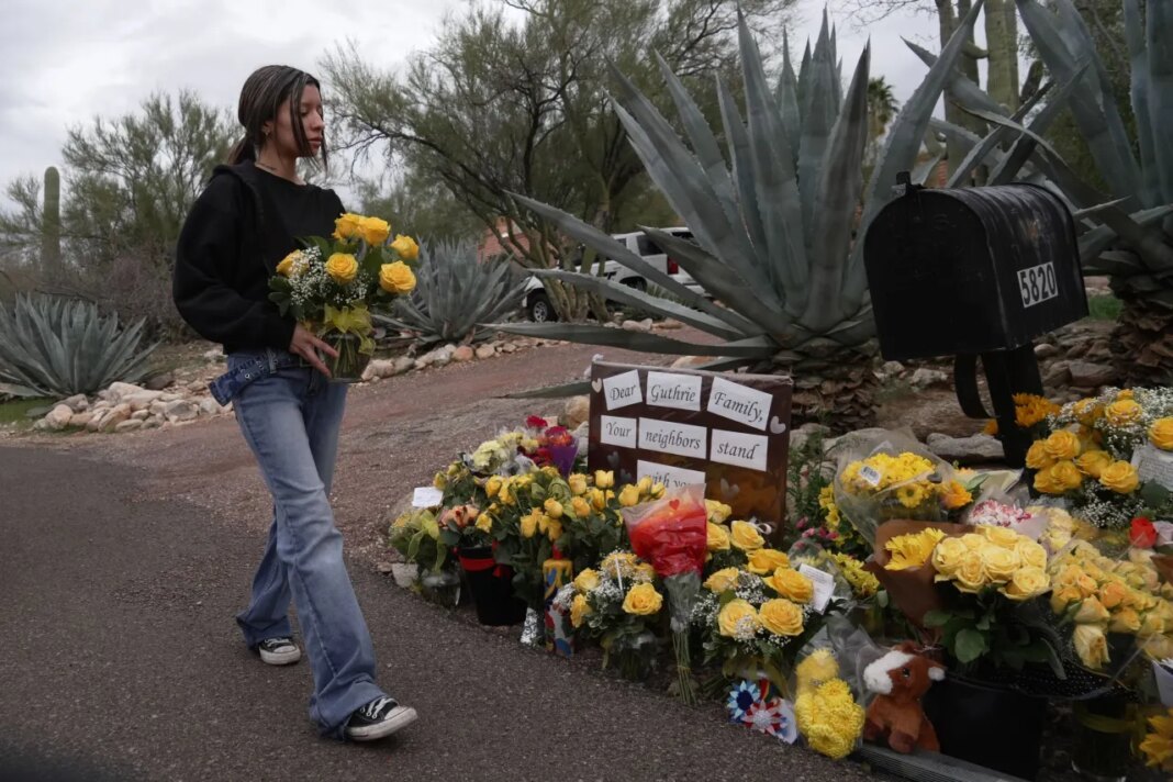 A person places flowers in front of Nancy Guthrie’s home in Tucson, Ariz., on Friday, Feb. 13, 2026. (AP Photo/Ty ONeil)