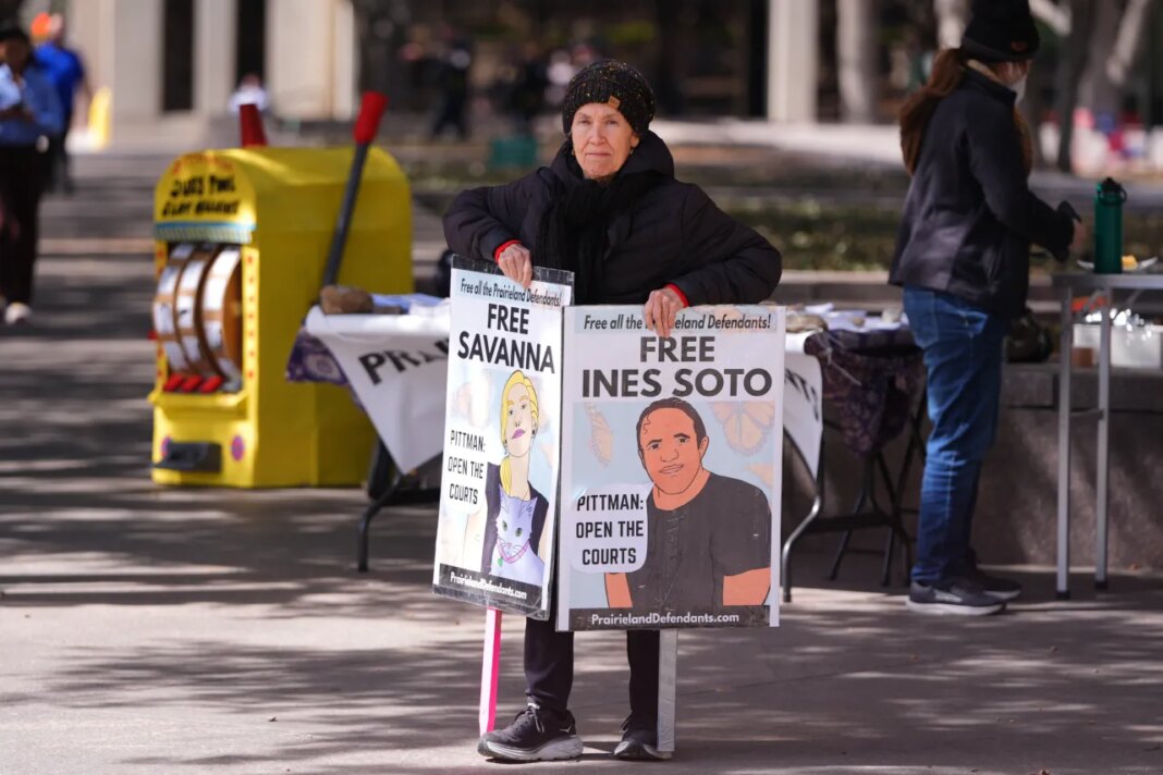 Susan Oakey holds a sign across the street from the Eldon B. Mahon U.S. Courthouse during a trial for nine people connected to a 2025 shooting outside an ICE detention facility Tuesday, Feb. 24, 2026, in Fort Worth, Texas. (AP Photo/LM Otero)