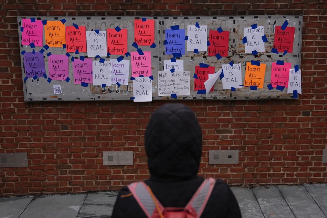FILE - A person views posted signs on the locations of the now removed explanatory panels that were part of an exhibit on slavery at President