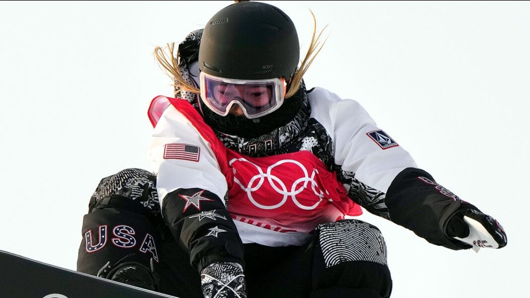 Why are Olympic snowboarders tucking their number bibs under their arms?