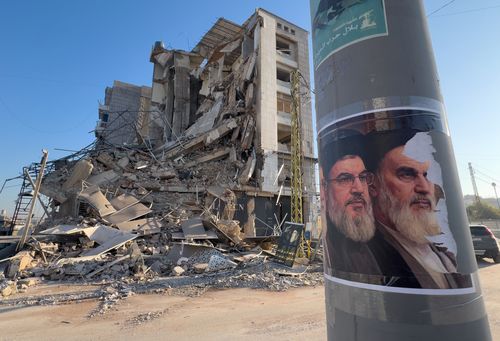 Portraits of late Hezbollah leader Sayyed Hassan Nasrallah and the late Iranian revolutionary founder Ayatollah Khomeini, are seen in front of a destroyed building that housed a branch of Al-Qard Al-Hassan, a non-bank financial institution run by Hezbollah, which was hit by an Israeli airstrike in Dahiyeh, Beirut's southern suburbs, Lebanon, Tuesday, March 10, 2026. (AP Photo/Hussein Malla)
