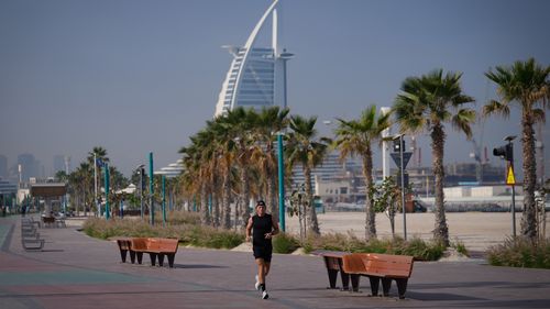 A man jogs along a beach with the Burj Al Arab luxury hotel seen in the background in Dubai, United Arab Emirates, Sunday, March 1, 2026. 