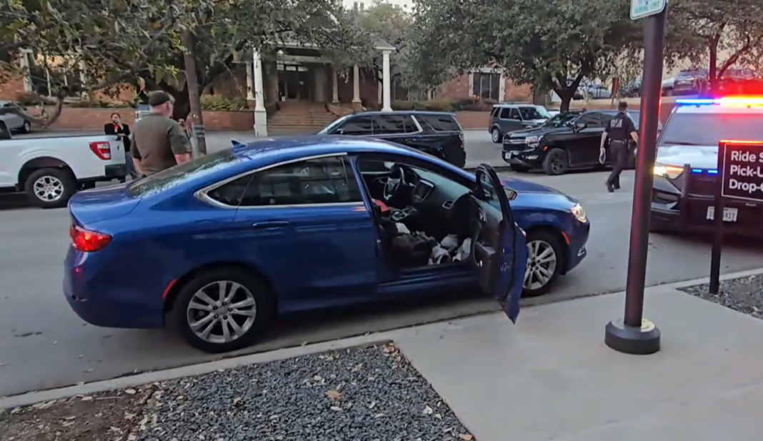 Police officer stands in front of a blue car with the passenger side door open