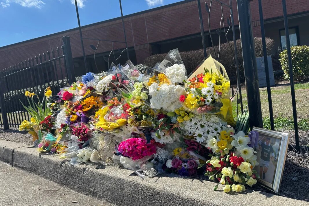 Flowers lie along a fence outside North Hall High School in Gainesville, Ga., on Monday, March 9, 2026. (AP Photo/Emilie Megnien)