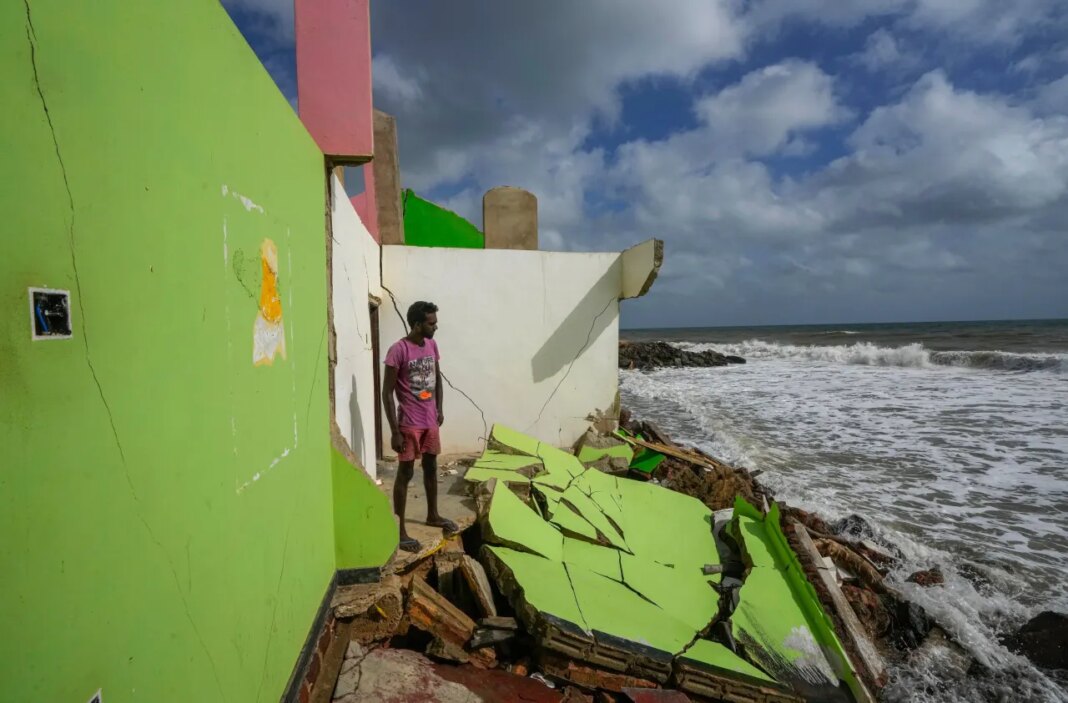 FILE - Dilrukshan Kumara looks at the ocean as he stands by the remains of his family