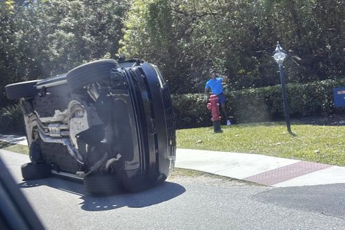 Golfer Tiger Woods stands by his overturned vehicle in Jupiter Island.