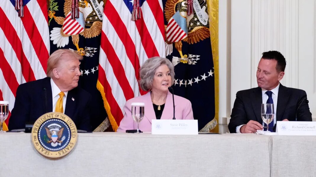White House Chief of Staff Susie Wiles speaks during a board meeting of the John F. Kennedy Memorial Center For The Performing Arts in the East Room of the White House, Monday, March 16, 2026, in Washington, as President Donald Trump and Kennedy Center President Richard Grenell, right, look on. (AP Photo/Alex Brandon)