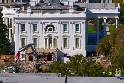Construction workers, right, atop the U.S. Treasury, watch as work continues on a largely demolished part of the East Wing of the White House.