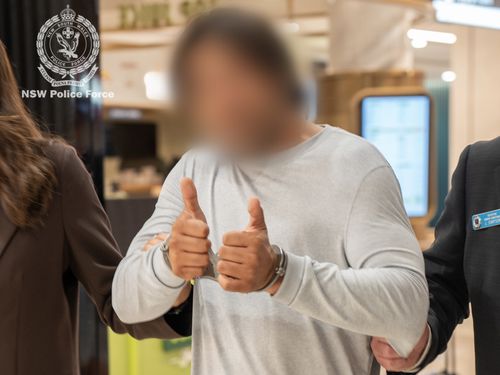 The man offered a thumbs-up sign to a camera at Sydney Airport.