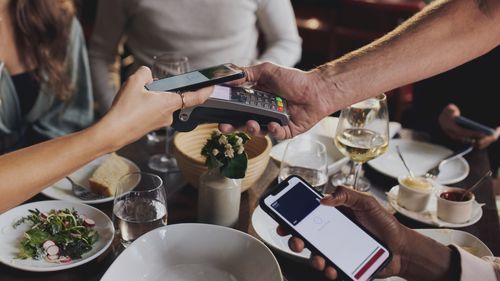 Friends paying contactlessly in restaurant