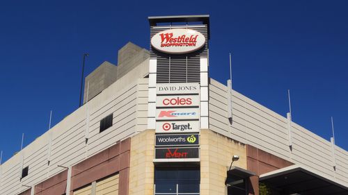 Sydney, Australia - October 2, 2014: Pedestrians and traffic waiting around an intersection beside Westfield Burwood. Westfield is a large chain of shopping malls, with over a hundred locations worldwide.