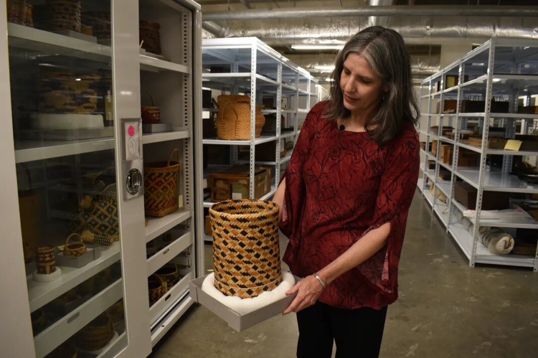 Nan Prince, the director of collections for the Mississippi Department of Archives History, holds a Native America basket in the archives, March 26, 2026, in Jackson, Miss. (AP Photo/Sophie Bates)