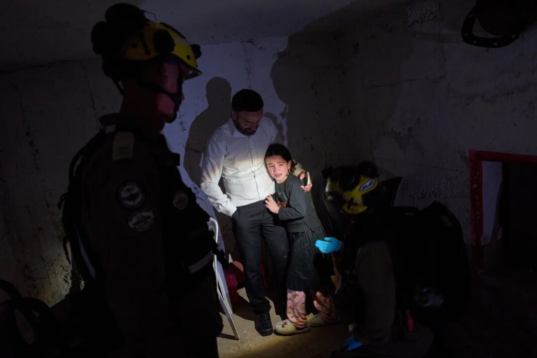 A young girl is comforted by her father and Israeli soldiers as they take cover in a bomb shelter during air raid sirens warning of incoming Iranian missile strikes in Bnei Brak, Israel, Wednesday, April 1, 2026. (AP Photo/Oded Balilty)