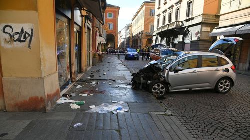 Blood is seen next to a destroyed car on a street of Modena, Italy, Saturday, May 16, 2026.