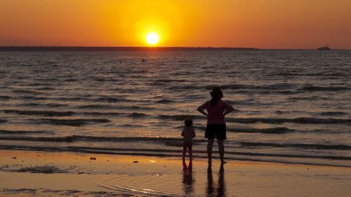 A woman and child watch the sun set at Mindil Beach in Darwin.