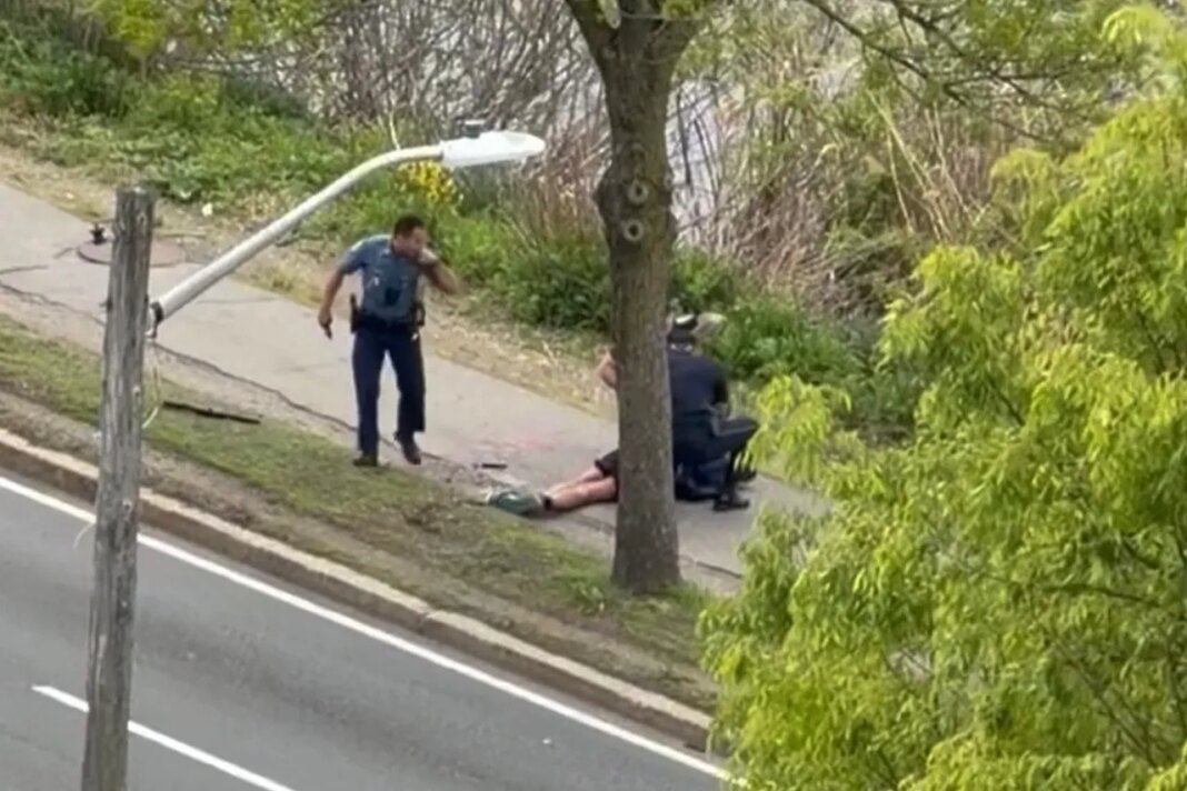 This image taken from video provided by Youssef Adel, shows law enforcement officers tending to the wounded gunman whom moments earlier fired weapons at a busy road in Cambridge, Mass. on Monday, May 11, 2026. (Youssef Adel via AP)
