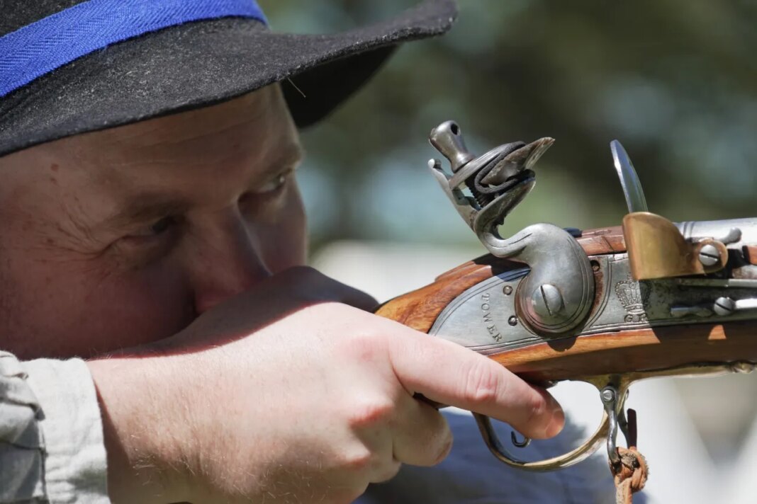 A.J. Drake, a historic interpreter, aims his Brown Bess flintlock replica musket during a Revolutionary War event in Halifax, N.C., on April 10, 2026. (AP Photo/Allen G. Breed)