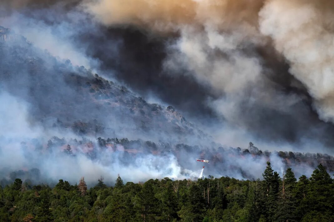 A helicopter provides bucket drops to assist firefighters battling the Gold Mountain Fire on the town line of Ouray and Ridgeway, Colo., Sunday, June 28, 2026. (Michael G. Seamans/The Gazette via AP)