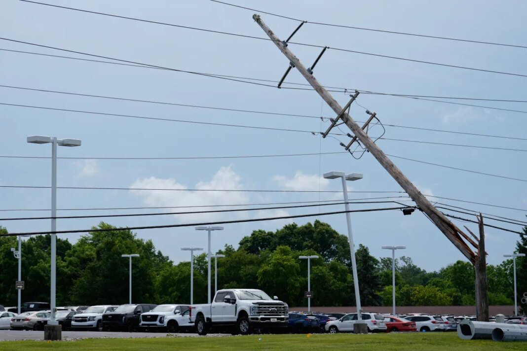 A snapped power pole hangs over a car lot at Joseph Cadillac in Florence, Ky, Thursday, June 18, 2026, after severe weather moved through the region. (AP Photo/Carolyn Kaster)