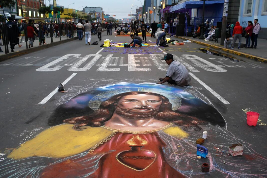 FILE - A man works on a chalk drawing depicting the Sacred Heart of Jesus, Oct. 28, 2017, in Lima, Peru. (AP Photo/Martin Mejia, File)