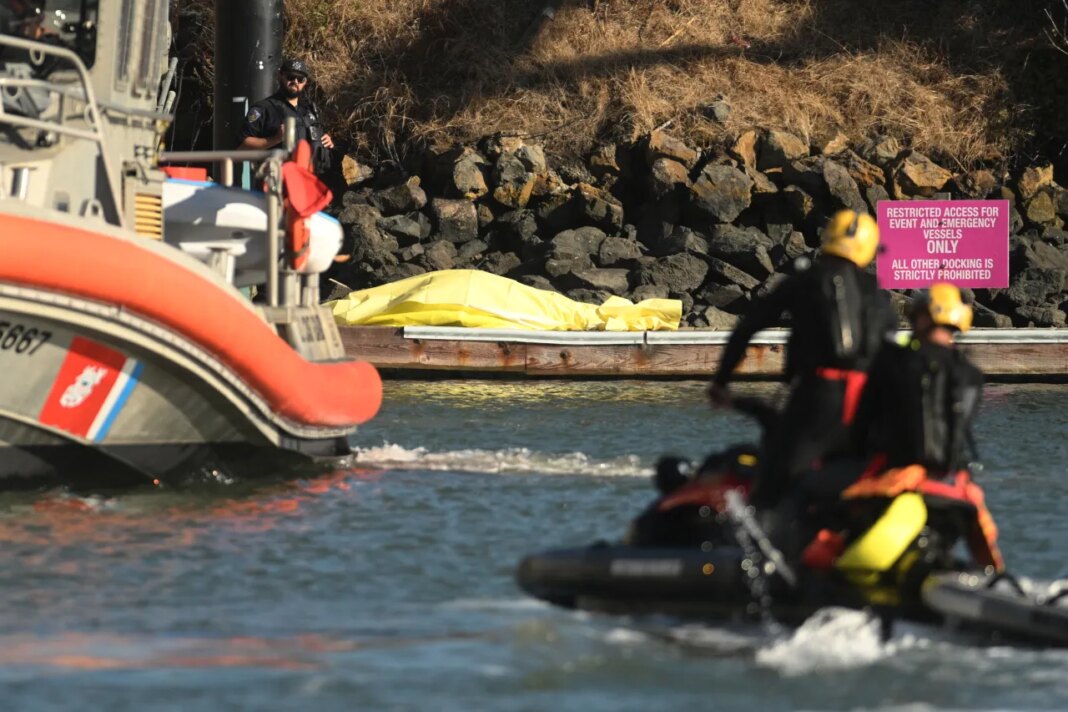 A body is covered with a tarp on a dock near the site of boat accident on Tuesday, July 14, 2026, in San Francisco. (AP Photo/Noah Berger)
