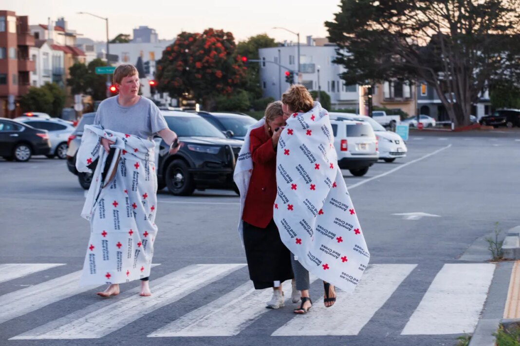 People cover themselves with American Red Cross blankets at Fort Mason, where the Red Cross has set up an assistance center for people impacted by a boat incident in the waters off San Francisco Tuesday, July 14, 2026. (Santiago Mejia/San Francisco Chronicle via AP)