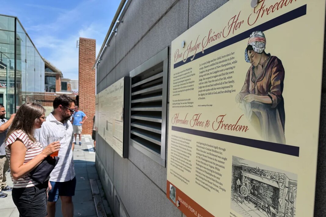 Visitors view the reinstalled educational panels about slavery at the site of President George Washington